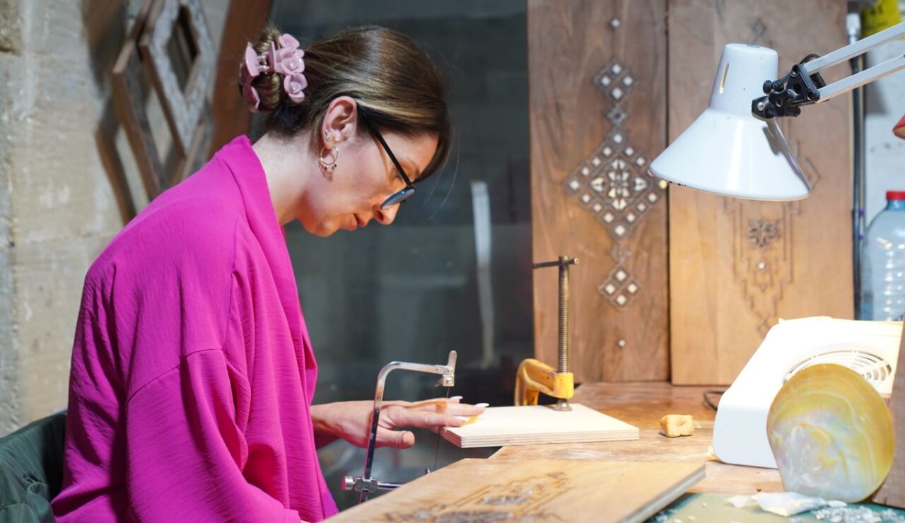 Une artisane concentrée grave une pièce de bois dans son atelier lumineux