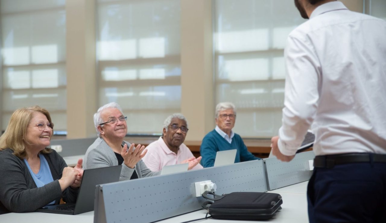 Adultes en session de formation informatique accompagnés par un formateur dans une salle claire