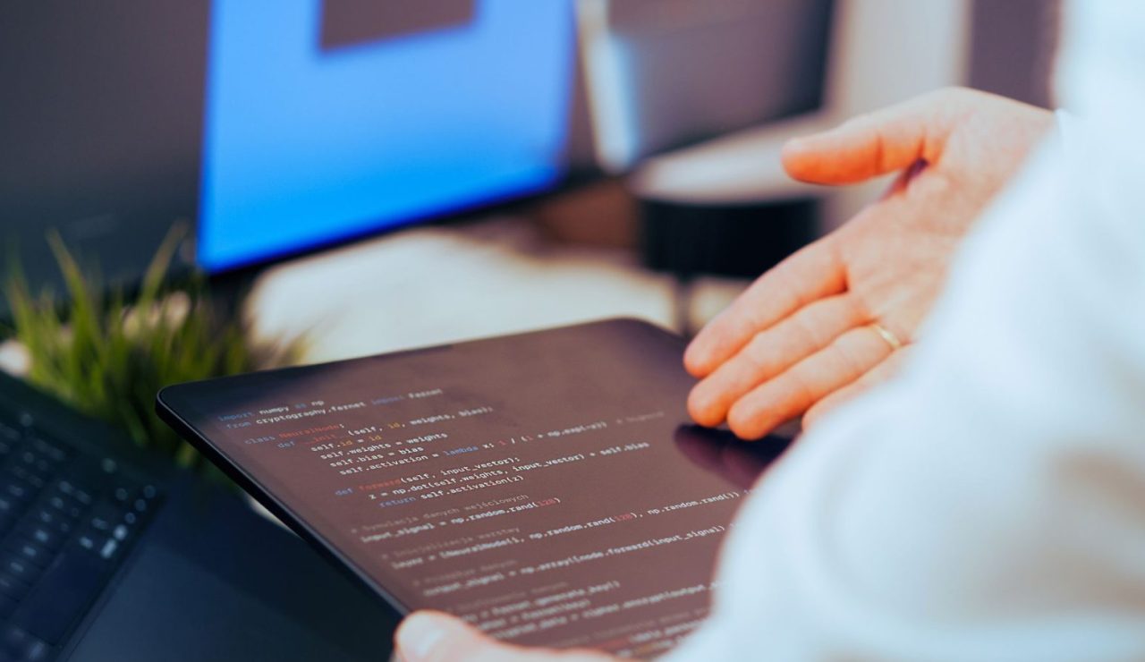 Professionnelle analysant des lignes de code sur une tablette dans un espace de travail moderne