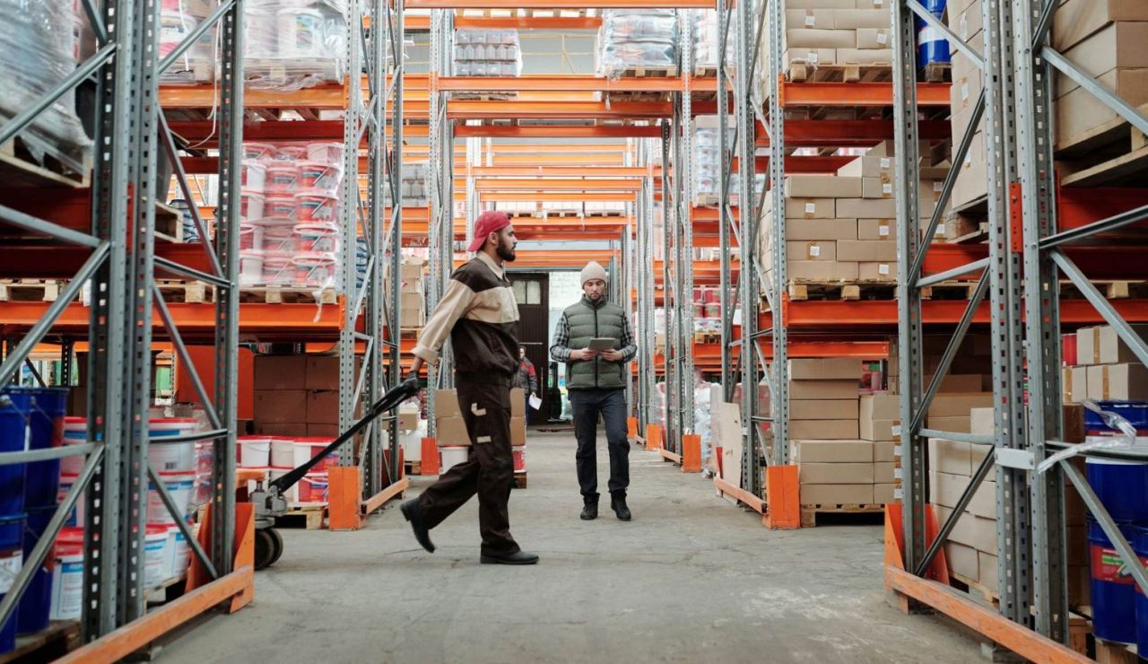 Deux salariés gérant les stocks dans une allée d'entrepôt logistique bien éclairée