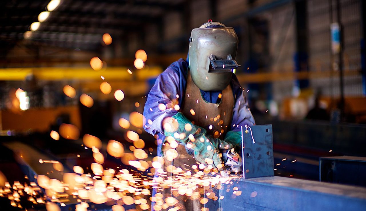 Soudeur en équipement de protection travaillant sur une pièce métallique dans un atelier industriel