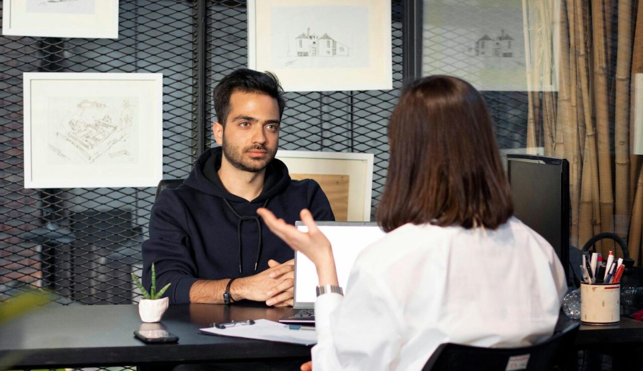 Une manager et un candidat assis face a face dans un bureau moderne, en pleine discussion pendant un entretien d'embauche