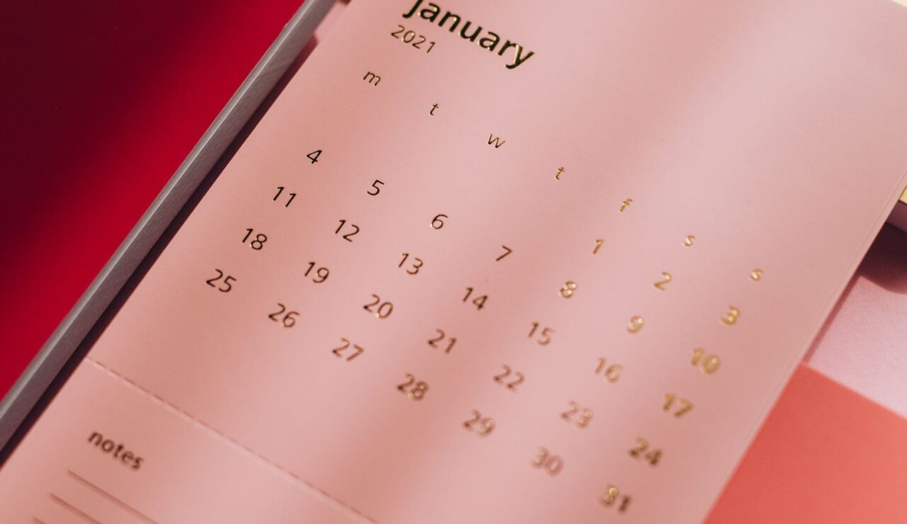 Un calendrier mural rose pose sur un bureau, page du mois de janvier