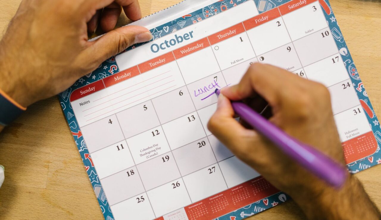 Une main note des dates de conges sur un calendrier de bureau au mois d octobre