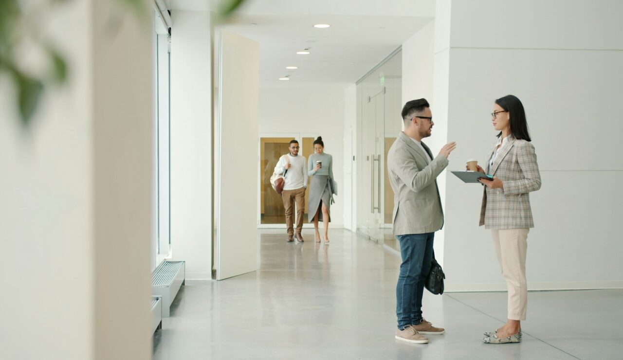 Deux collègues échangent dans le couloir de leur entreprise, étape clé d'une mobilité interne