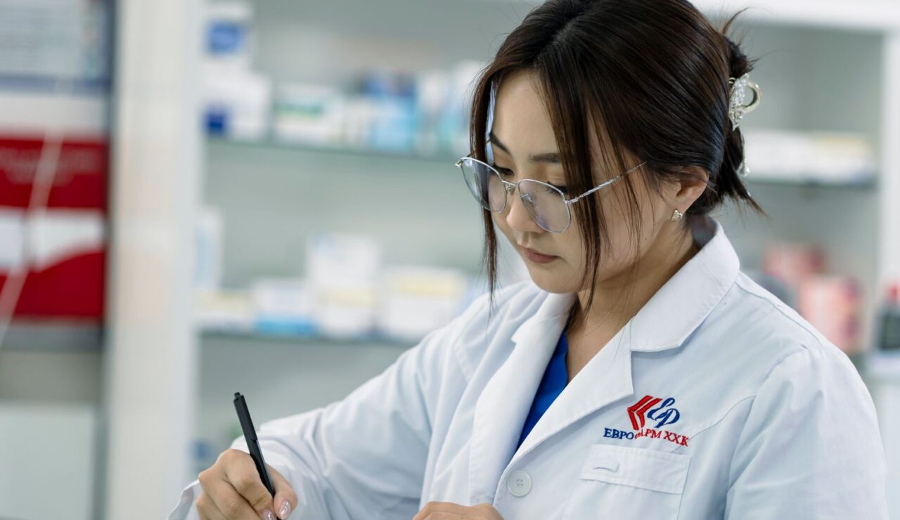 Une pharmacienne en blouse blanche prepare une commande au comptoir d une pharmacie lumineuse
