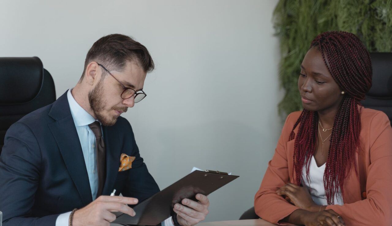 Un recruteur prend des notes face a une candidate en veste rose lors d un entretien d embauche
