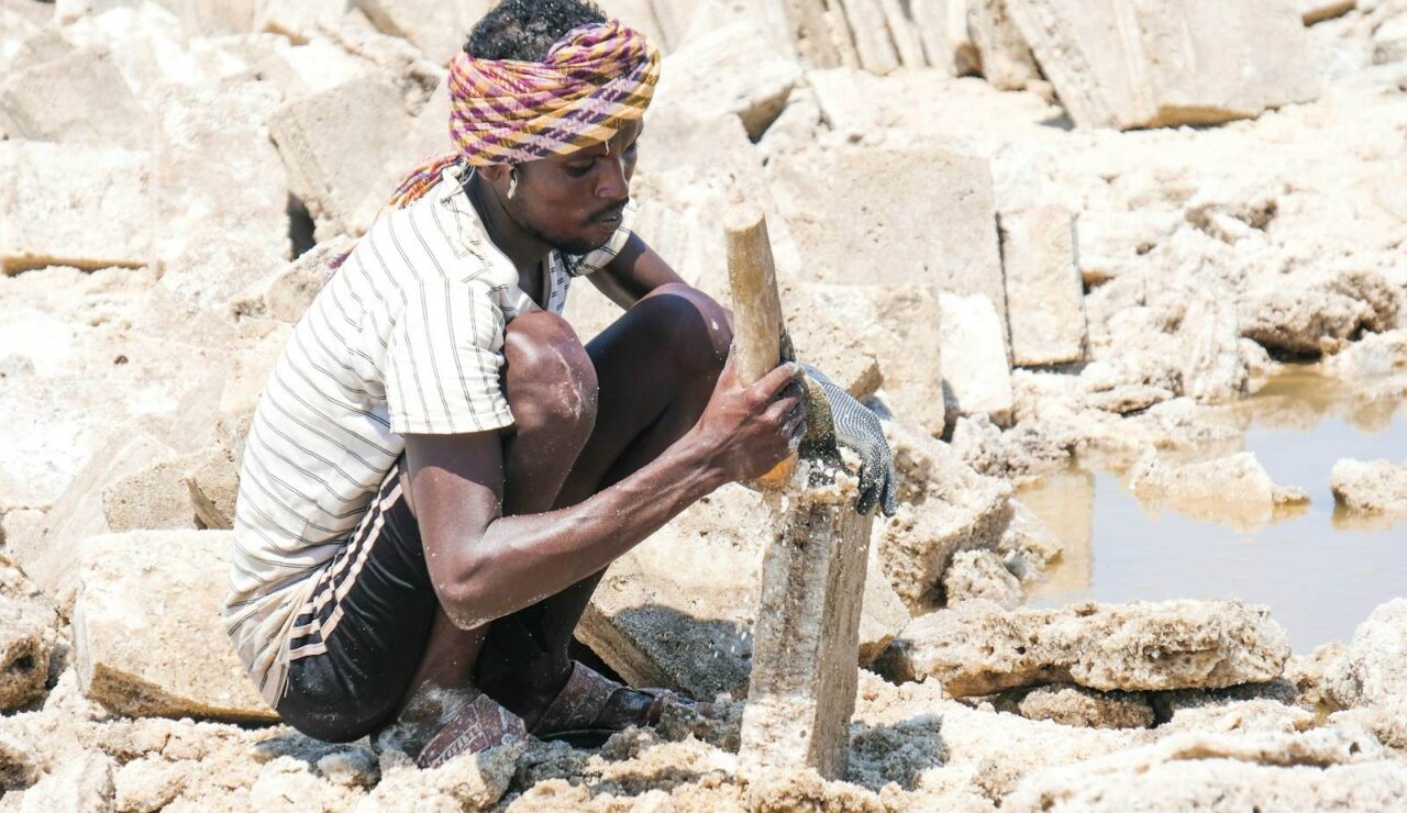 Un ouvrier coiffé d'un turban découpe des blocs de sel à la main dans une saline en Éthiopie